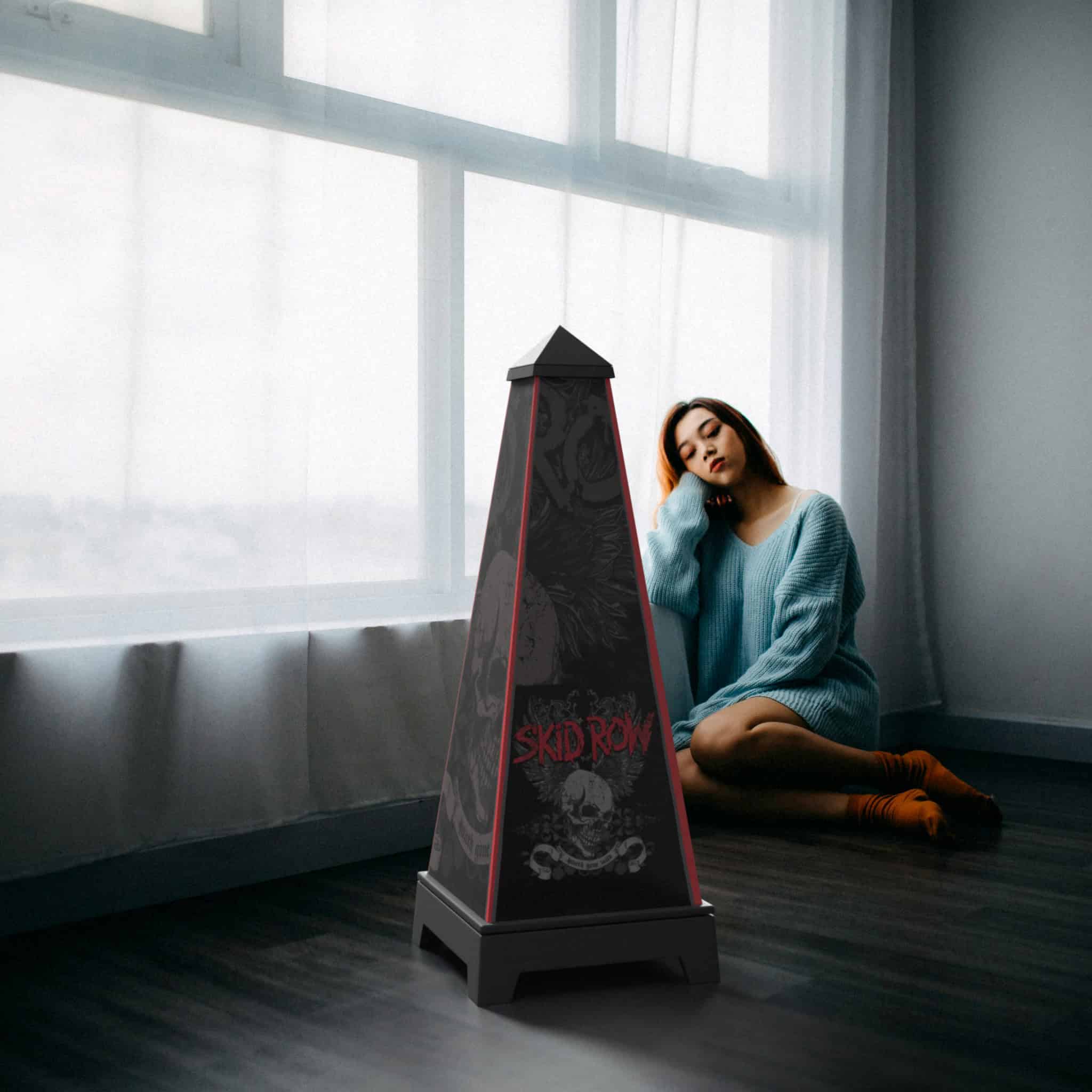XOUNTS-Soundsystem in Schwarz mit einem Skid Row Youthskull Style Cover, das prominent in einem modernen Raum vor einer Frau steht