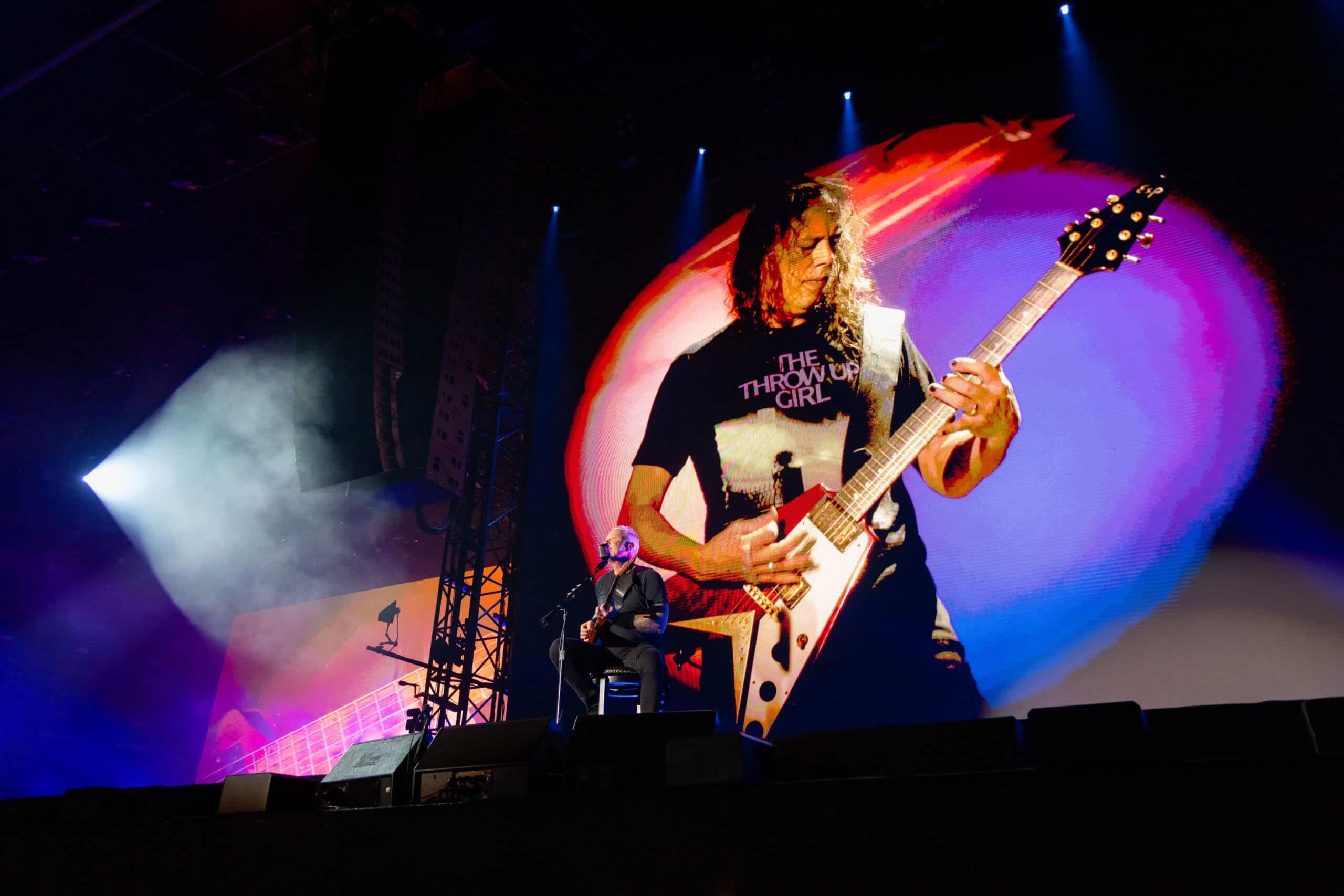 Sieben Personen stehen eng beieinander vor dunklem Hintergrund und blicken ernst in die Kamera.