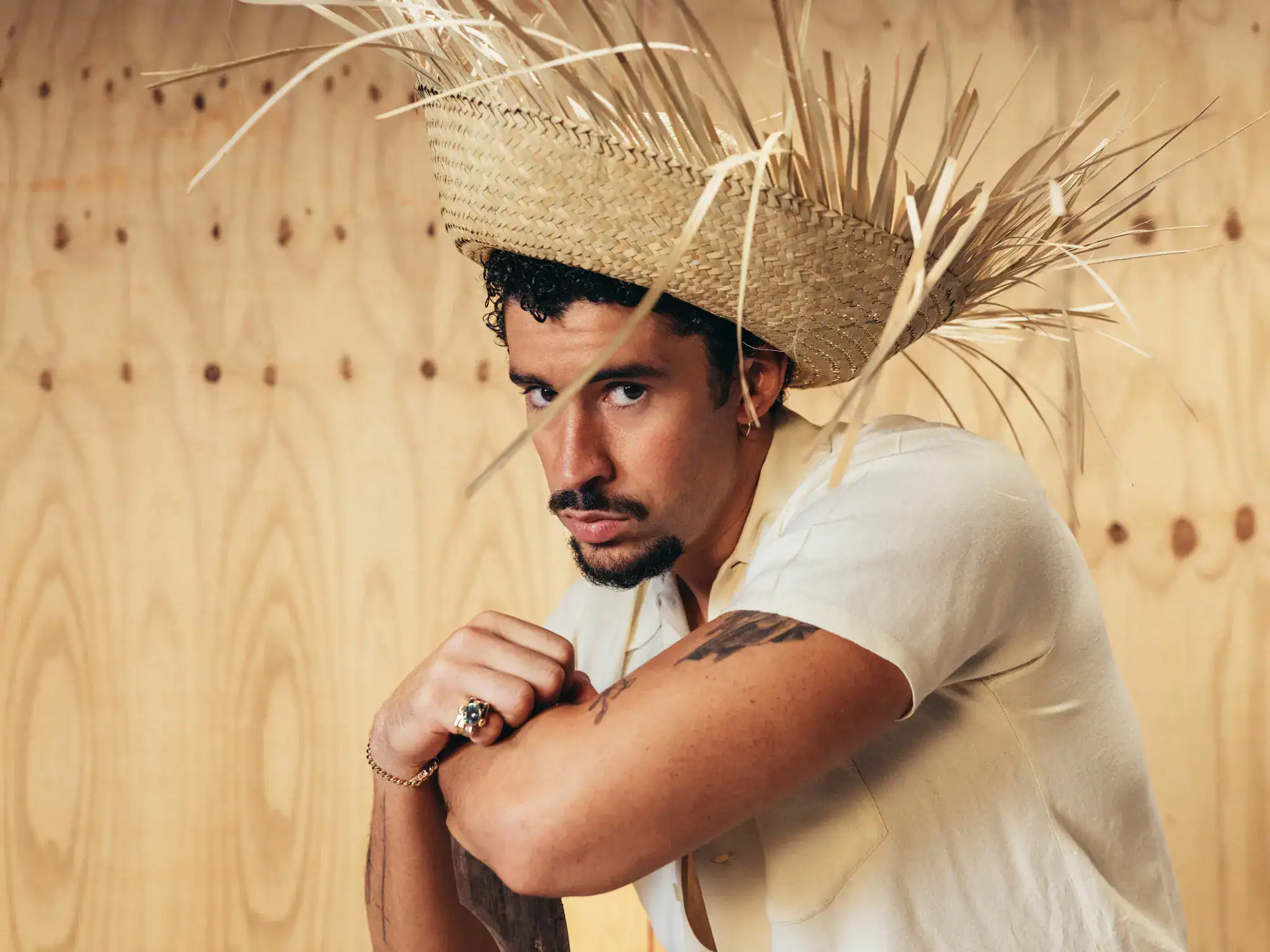 Das Bild zeigt ein Porträt eines Mannes vor einer hellen Holzwand mit sichtbarer Maserung.