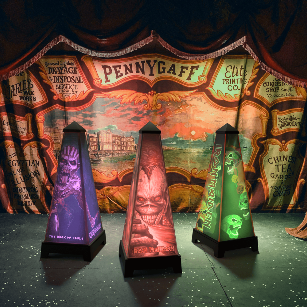 Drei XOUNTS Soundsysteme mit Iron Maiden StyleCovern stehen vor einem Zirkushintergrund. Die Lautsprecher zeigen beleuchtete Eddie-Motive in Violett, Rot und Grün. Der Vintage-Jahrmarkthintergrund verstärkt die rockige Atmosphäre der Iron Maiden Designs